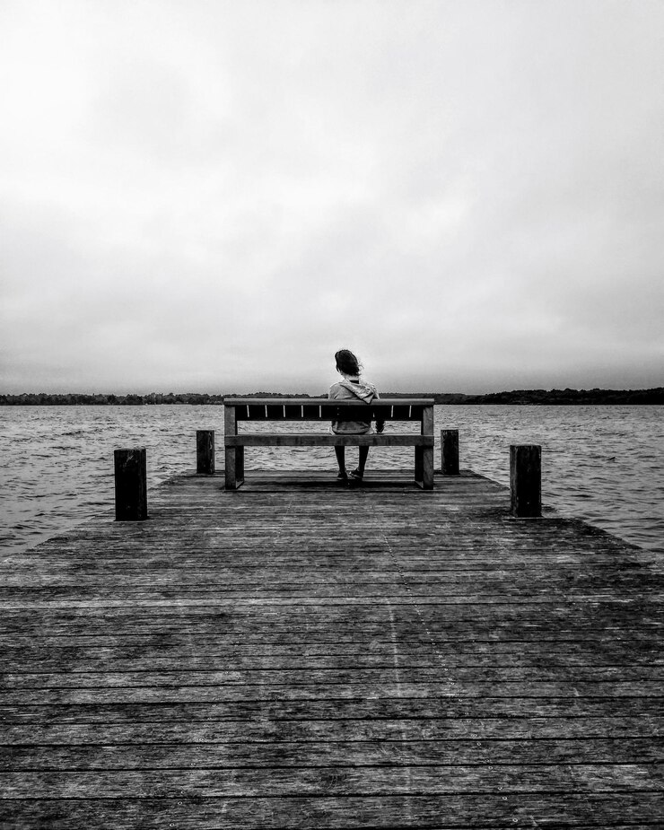 Photo rear view of lonely girl sitting on pier over sea against sky