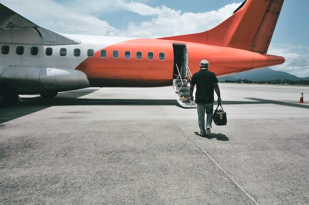 Foto vista posteriore di un uomo sulla pista dell'aeroporto contro il cielo