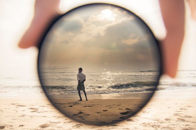 Foto vista posteriore di un uomo sulla spiaggia contro il cielo