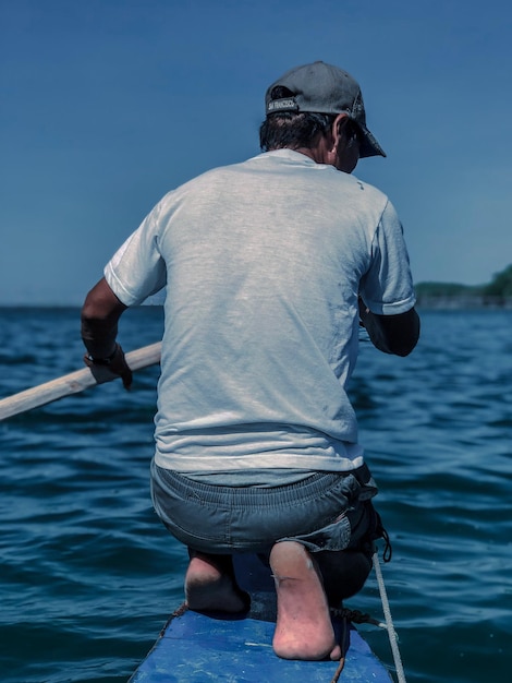 Photo rear view of man boating in sea against clear sky