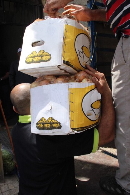 Photo rear view of a man carrying potatoes in boxes