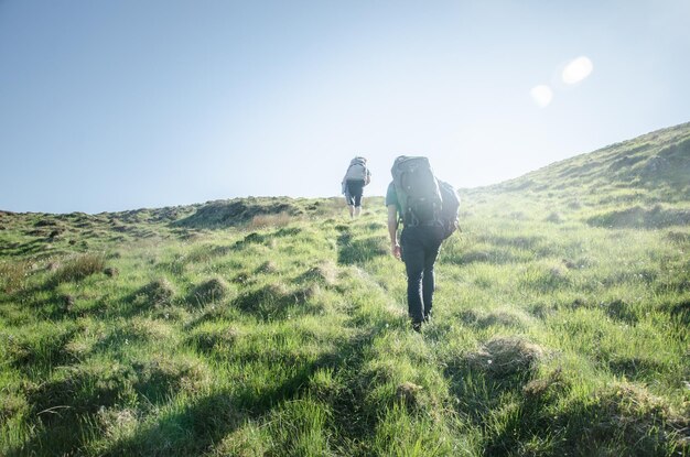 Rear view of man climbing mountain against sky