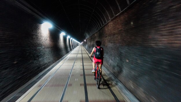 Photo rear view of man cycling in tunnel