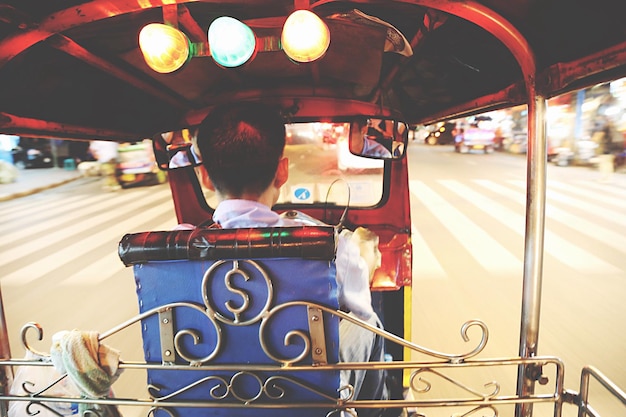 Photo rear view of man driving tuktuk on road