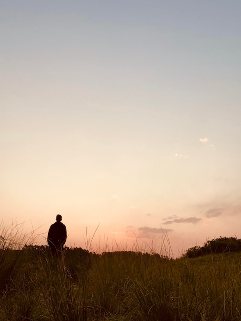 Foto vista posteriore di un uomo sul campo contro il cielo durante il tramonto