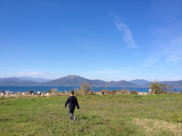 Rear view of man on field against sky