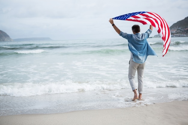 해변에서 미국 국기를 들고 남자의 뒷 모습