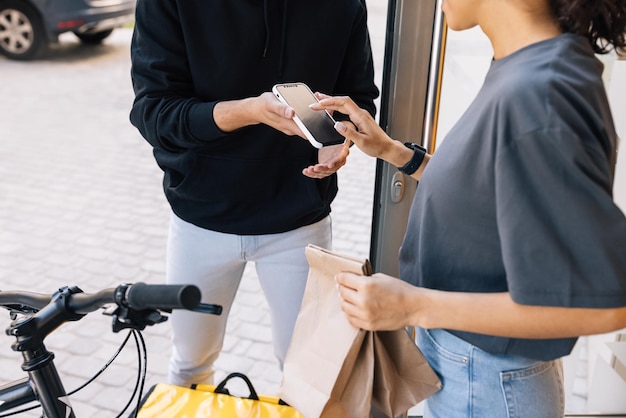 街の通りで立っている男性が携帯電話を握っている後ろの景色