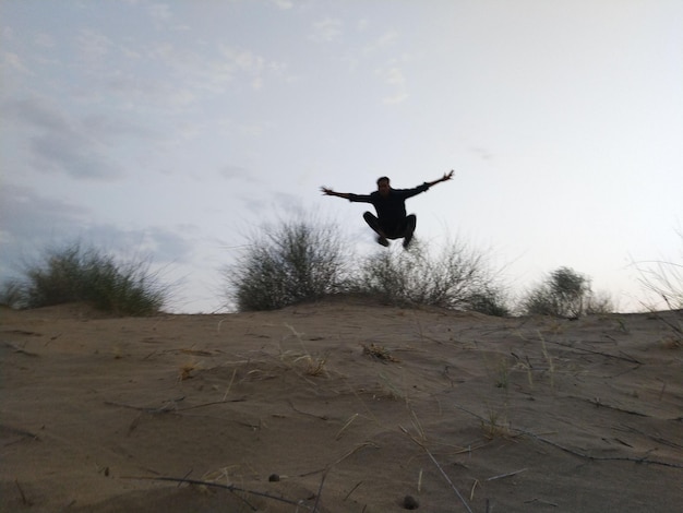 Photo rear view of man jumping on sand