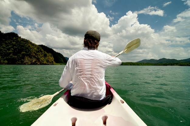 Rear view of man kayaking in sea Man paddling the sea kayak in the tropical bay