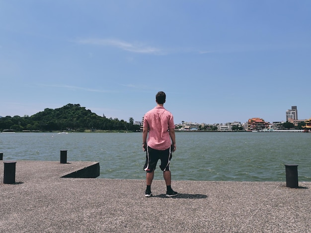 Foto vista posteriore di un uomo che guarda il lago contro il cielo