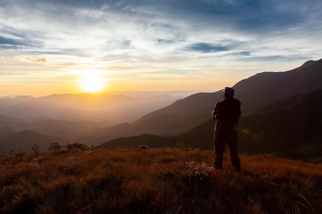 Rear view of man looking at mountains against sky during sunset