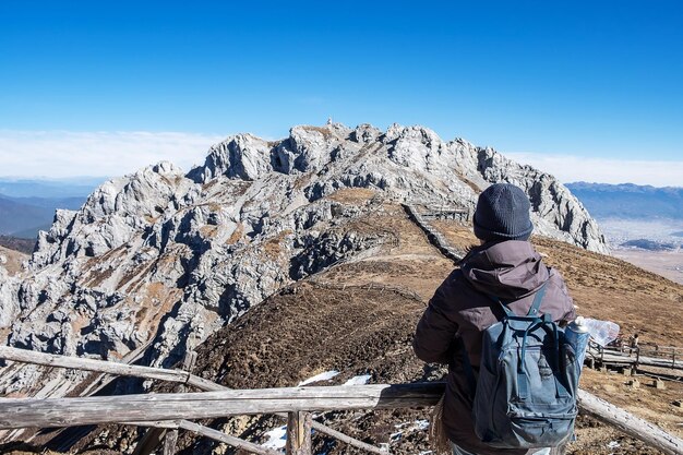 Rear view of man looking at rock against sky