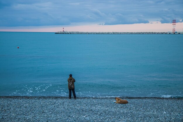 Foto vista posteriore di un uomo che guarda il mare contro il cielo