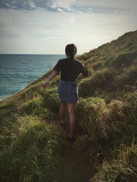 Rear view of man looking at sea against sky