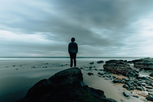 Foto vista posteriore di un uomo che guarda il mare contro il cielo