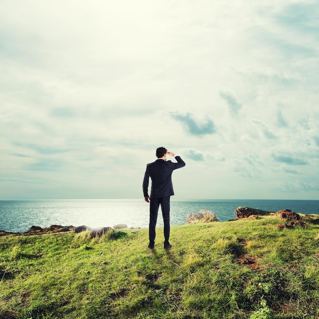 空を背景に海を見ている男の後ろの景色