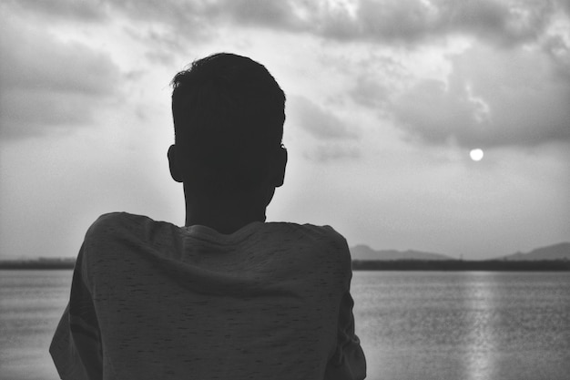 空に照らして海を見つめる男の後ろの景色