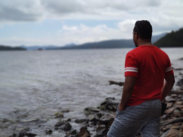 Foto vista posteriore di un uomo che guarda la riva del mare