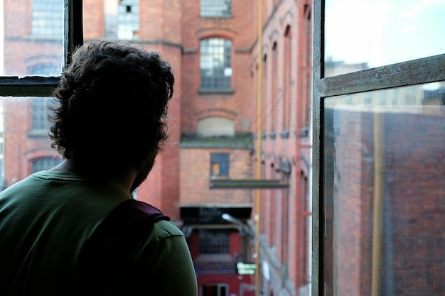 Rear view of man looking through window
