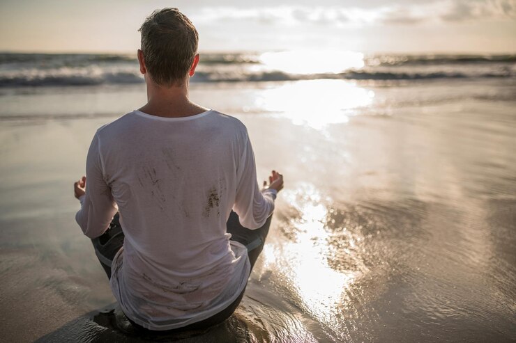 Photo rear view of man meditating at beach during sunset