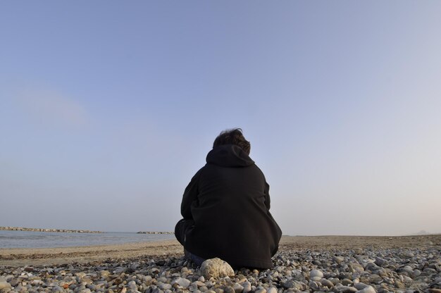 Foto vista posteriore di un uomo che si affaccia su una spiaggia tranquilla