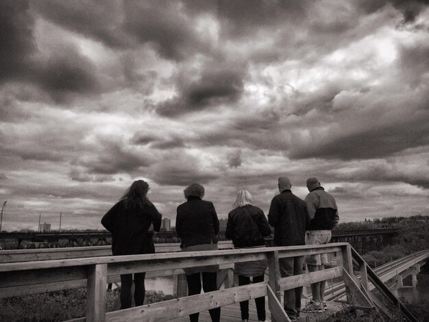 Rear view of man overlooking cloudy sky