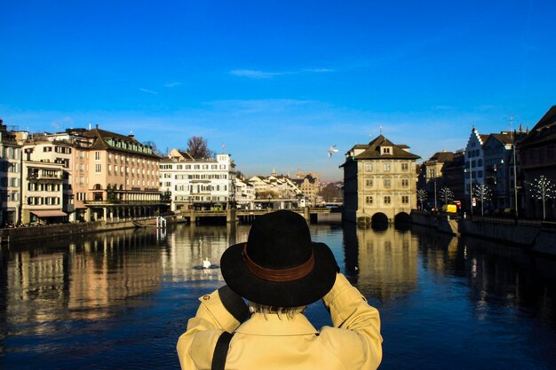 Foto vista posteriore di un uomo che si affaccia sul fiume contro le strutture costruite