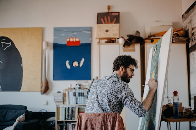 rear view of man painting on canvas at home