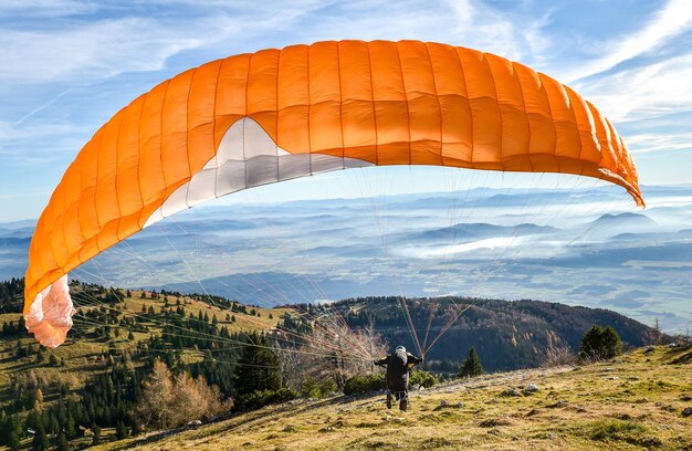 Rear view of man paragliding on mountain against sky