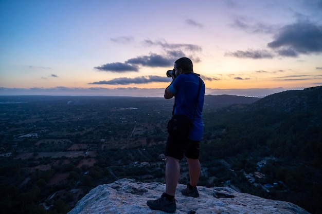 Foto vista posteriore di un uomo che fotografa contro il cielo durante il tramonto