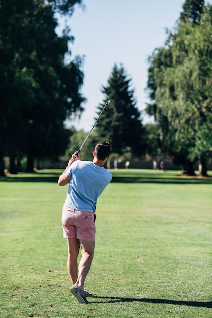 Rear view of man playing golf on field