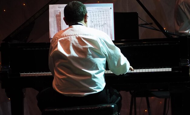 Foto vista posteriore di un uomo che suona il pianoforte