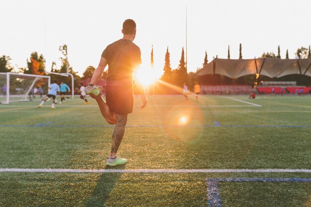 夕暮れの場でサッカーをしている男の後ろの景色