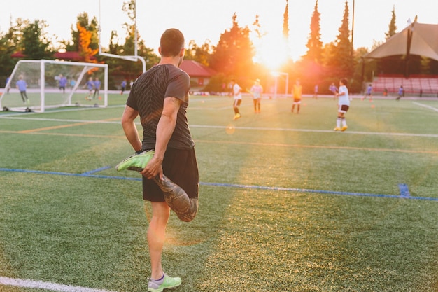 夕暮れの場でサッカーをしている男の後ろの景色