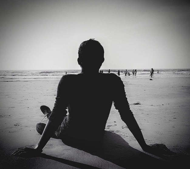 Foto vista posteriore di un uomo che si rilassa sulla spiaggia sabbiosa