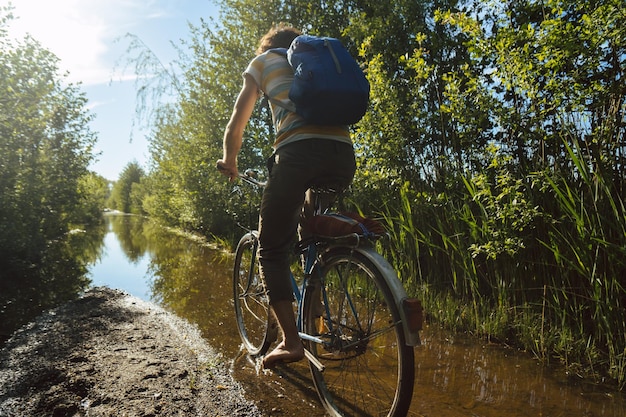 rear view of man riding bicycle on water amidst plants