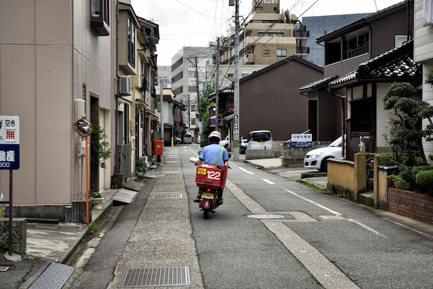 Photo rear view of man riding motor scooter on road in city