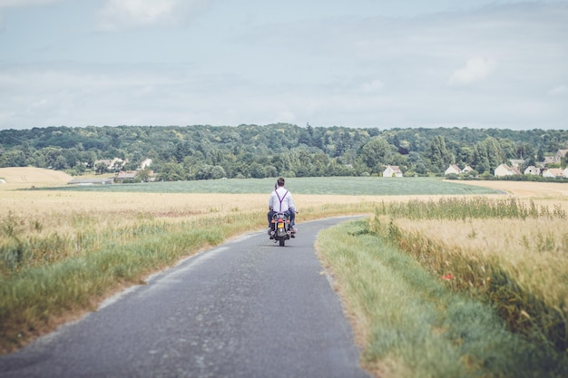 Photo rear view of man riding motorcycle on road against sky
