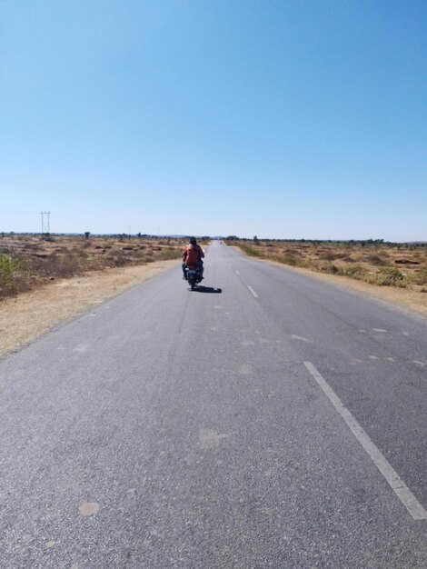 Rear view of man riding motorcycle on road against sky