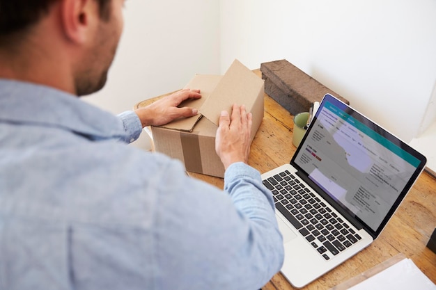 Rear View Of Man Running Business From Home Dispatching Goods