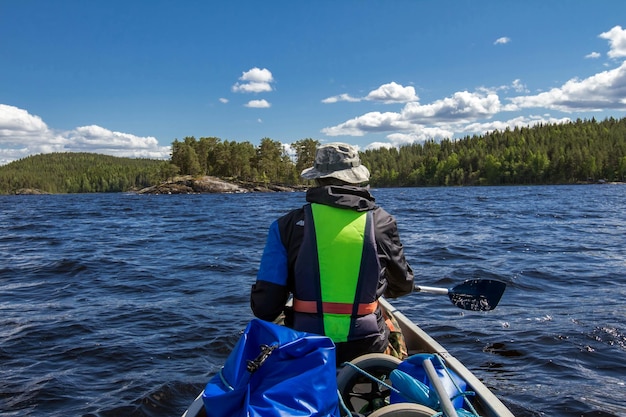 Rear view of man sailing on boat in river against sky