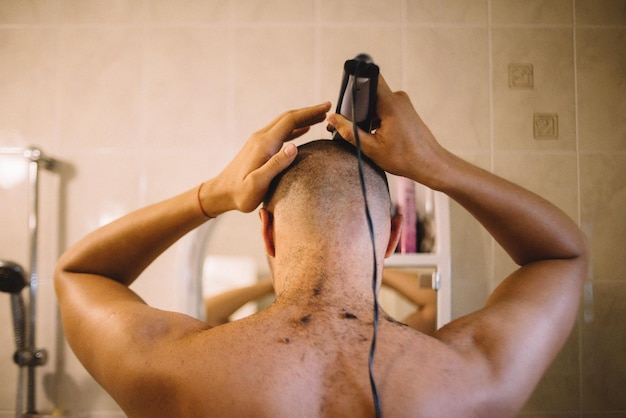 Foto vista posteriore di un uomo che si rascia la testa in bagno