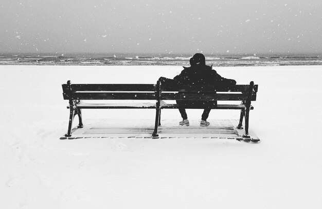 Foto vista posteriore di un uomo seduto su una panchina in inverno