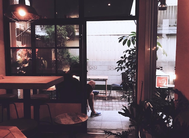 Photo rear view of man sitting by doorway at restaurant