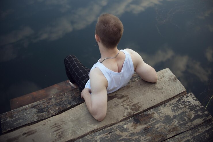 Photo rear view of man sitting by lake