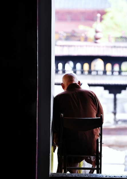 Photo rear view of man sitting on chair at doorway