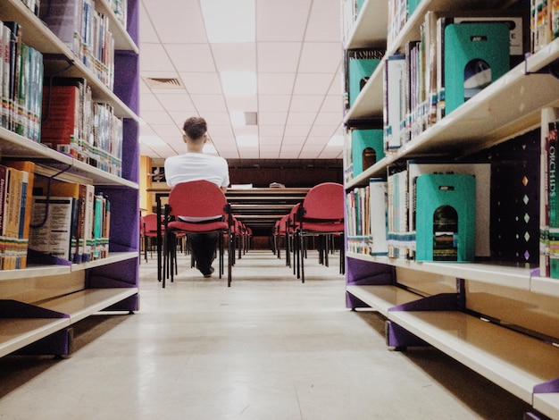 Photo rear view of man sitting on chair in library