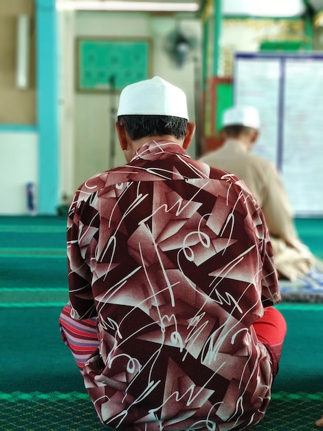 Photo rear view of man sitting in mosque