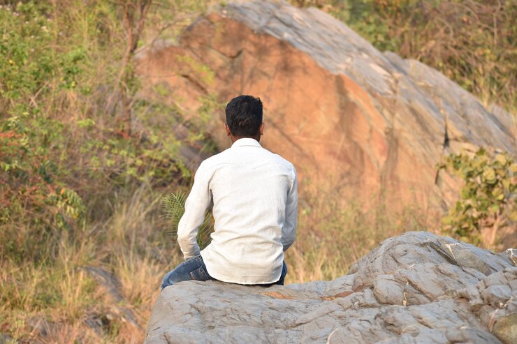 फोटो rear view of man sitting on rock